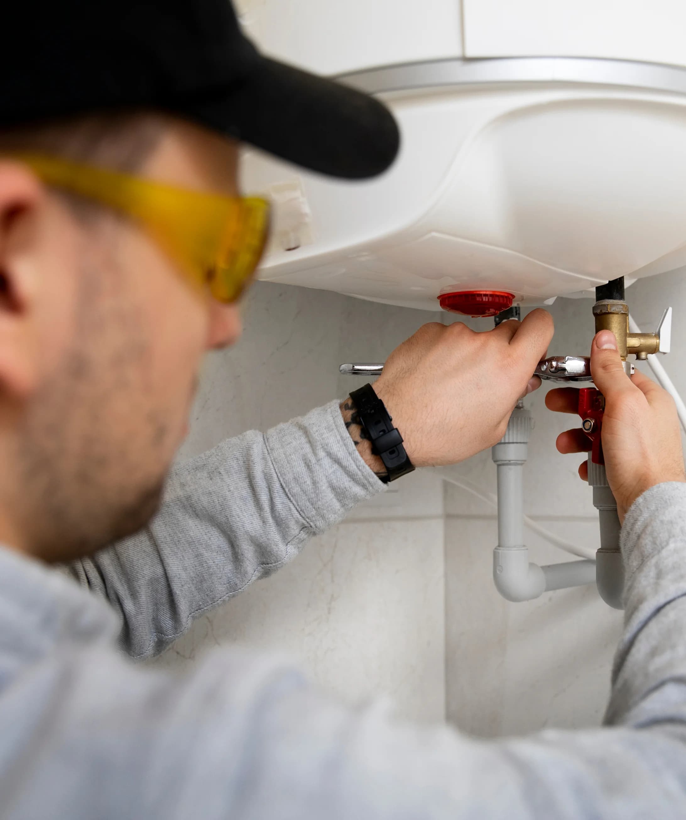 A water heater technician is fixing a conventional water heater.